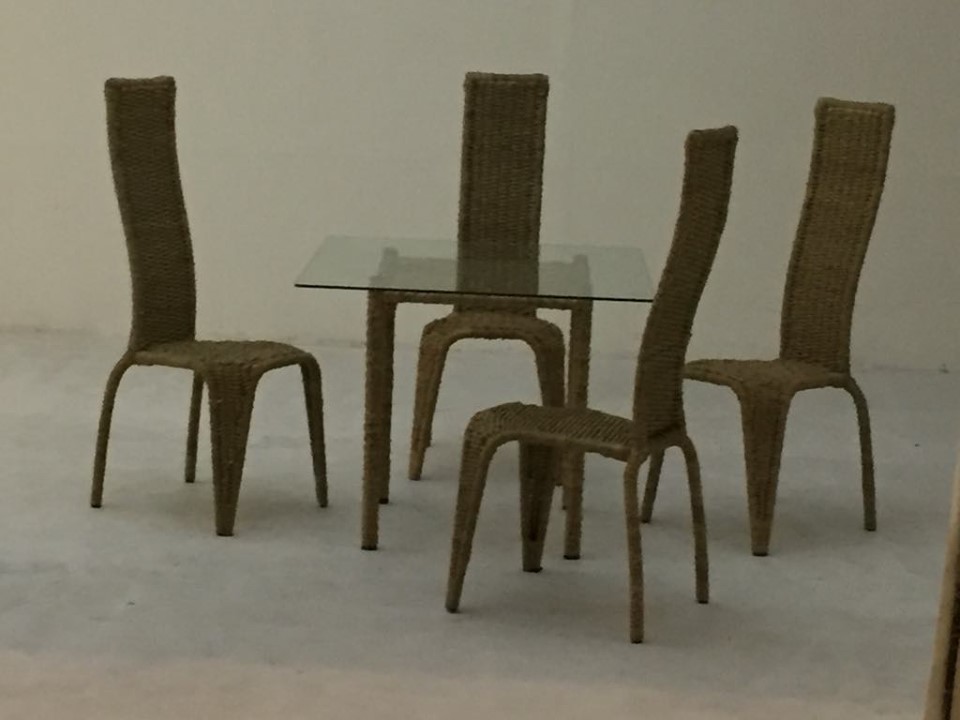 Dining set containing a square glass table and four rattan chairs, designed for hotels.